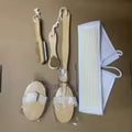 A set of natural wood and white plastic bath scrubbing tools, including two oval scrubbing pads, a wooden brush, and a white plastic scrubber, laid out on a brown background.